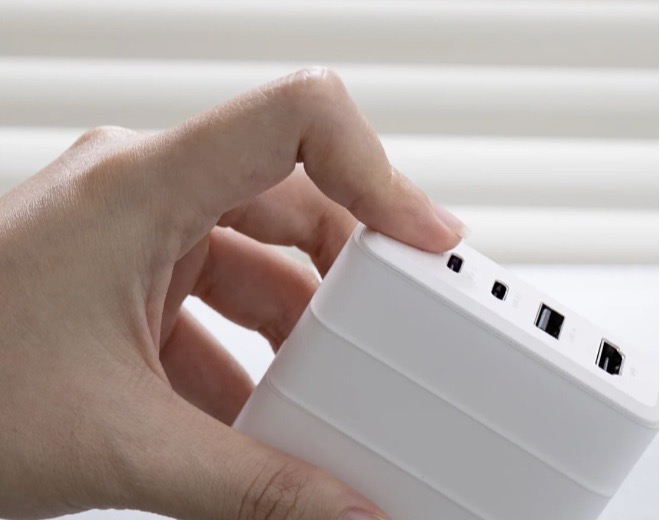 A hand connecting accessories to a stacked Bricbloc system