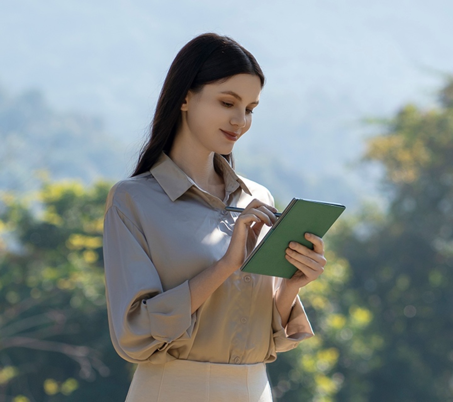 A woman writing on a tablet outdoors in daylight